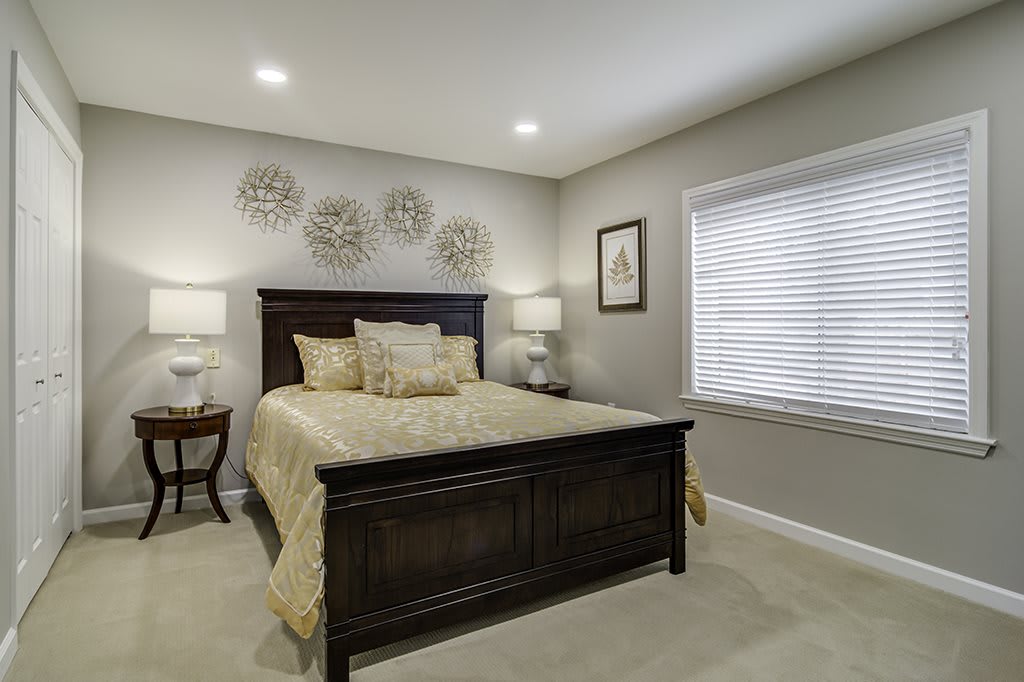 A cozy and elegant bedroom with a dark wooden bed frame, beige bedding, and soft lighting.