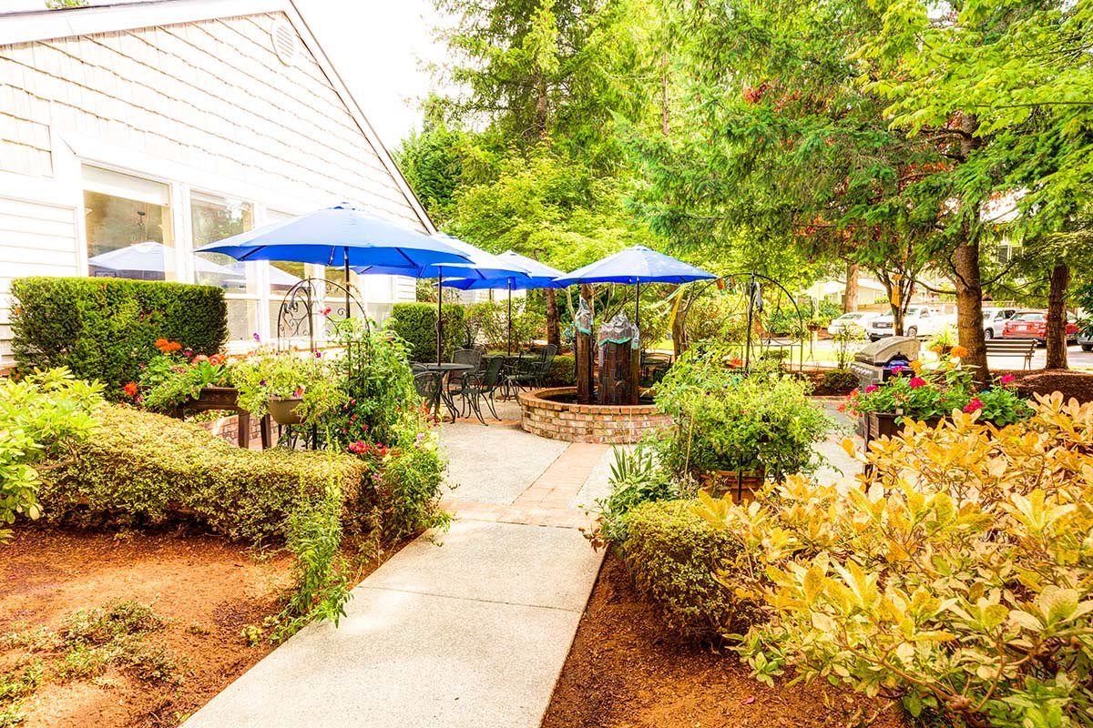 A cozy outdoor patio with blue umbrellas surrounded by lush greenery.