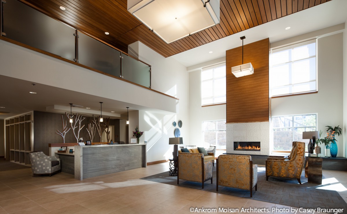 A modern lobby with a fireplace, contemporary furniture, and large windows allowing natural light.