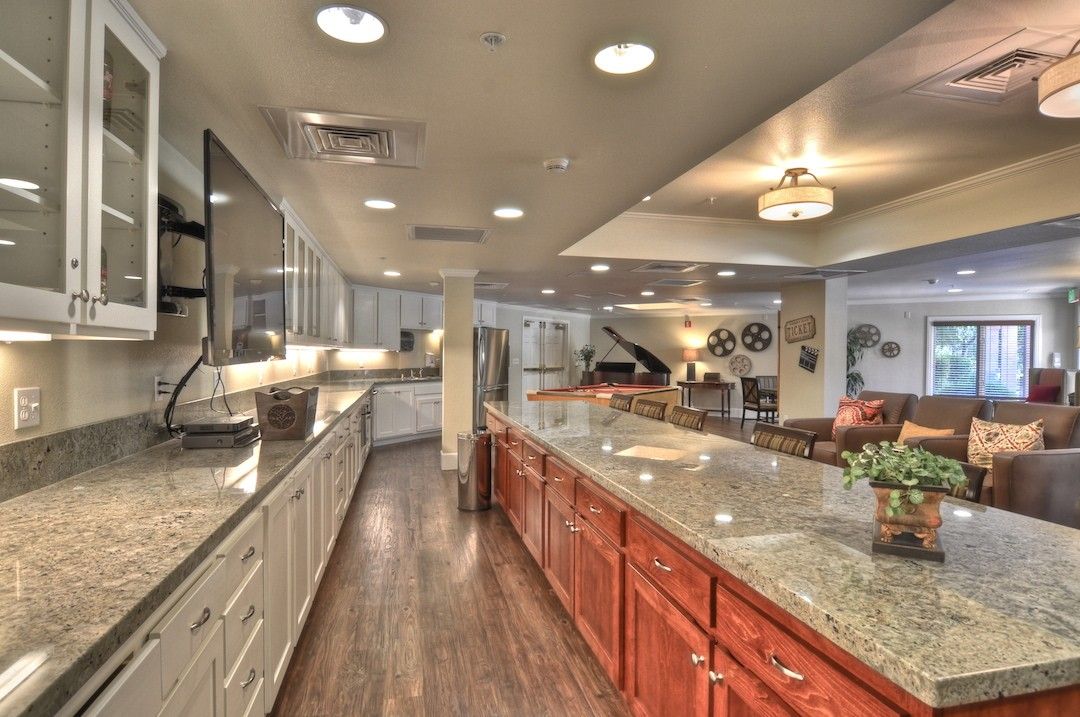 A spacious and modern kitchen featuring granite countertops and wood flooring with an open floor plan.