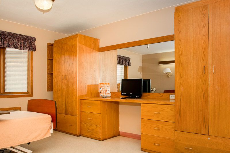 A cozy hotel room featuring wooden furniture, including a wardrobe and a desk with a television.