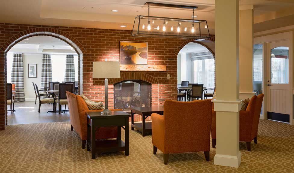 A cozy living room with a fireplace, featuring comfortable seating and a warm brick interior.