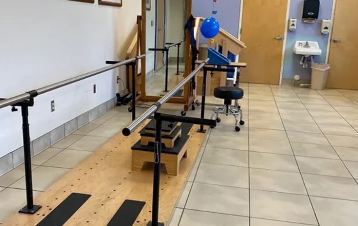 A physical therapy room featuring parallel bars and exercise equipment.
