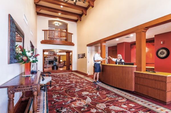 A hotel lobby with a reception desk and an intricate carpet design.