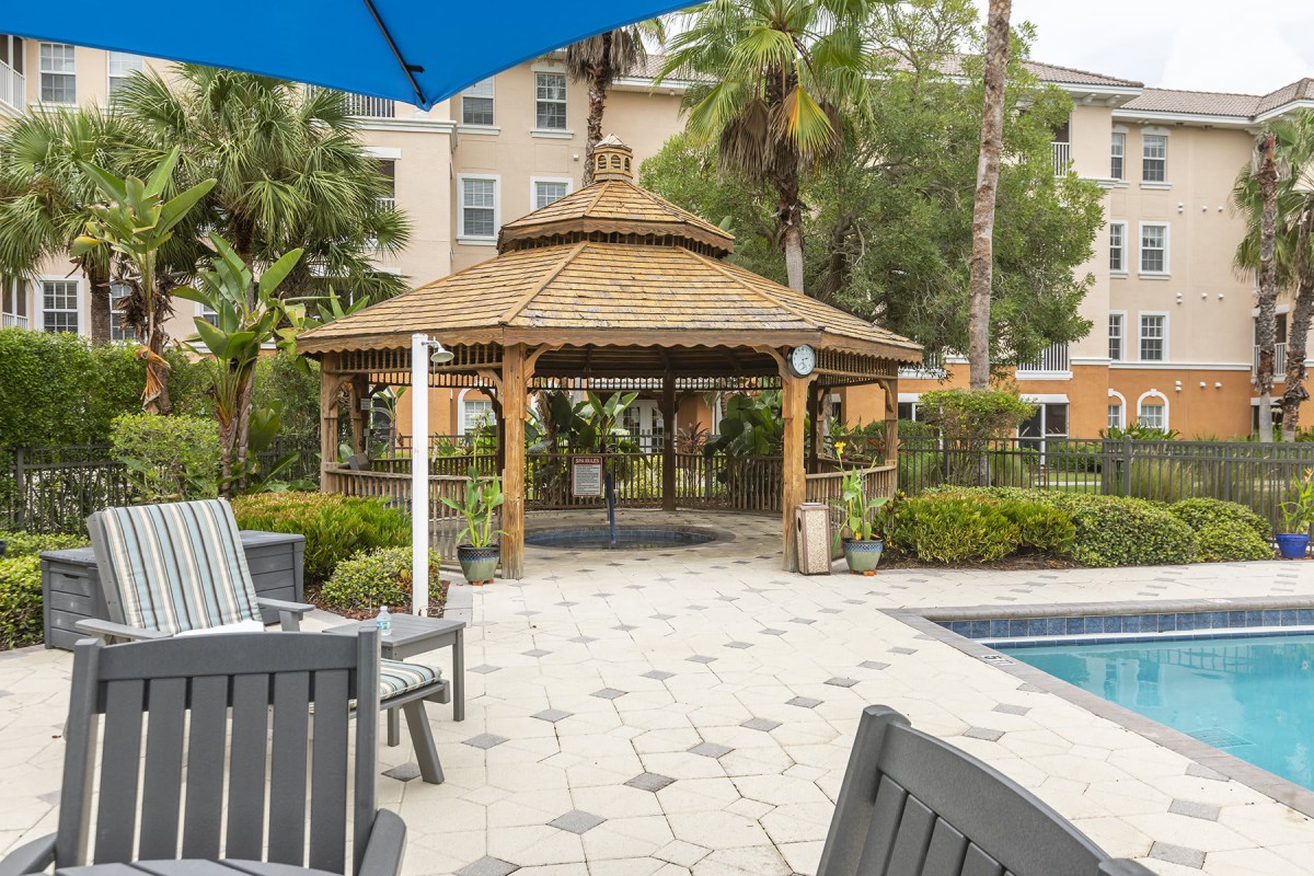 A cozy gazebo near a poolside in a tropical outdoor setting.