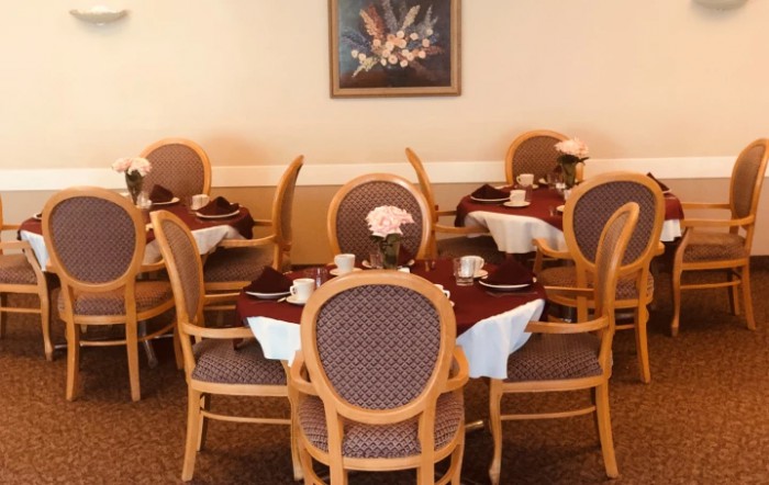 An elegant dining area featuring neatly set tables with comfortable chairs and a framed picture on the wall.