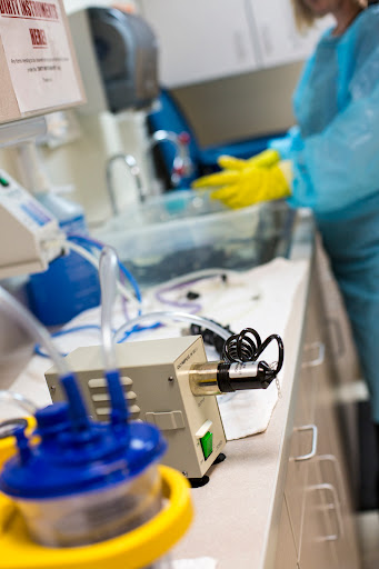 A scientist in protective gear working at a laboratory table with various medical equipment and glassware.