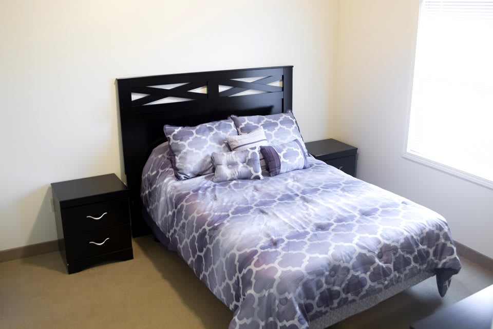 A cozy bedroom with a bed featuring a geometric patterned comforter and matching pillows, flanked by two nightstands.