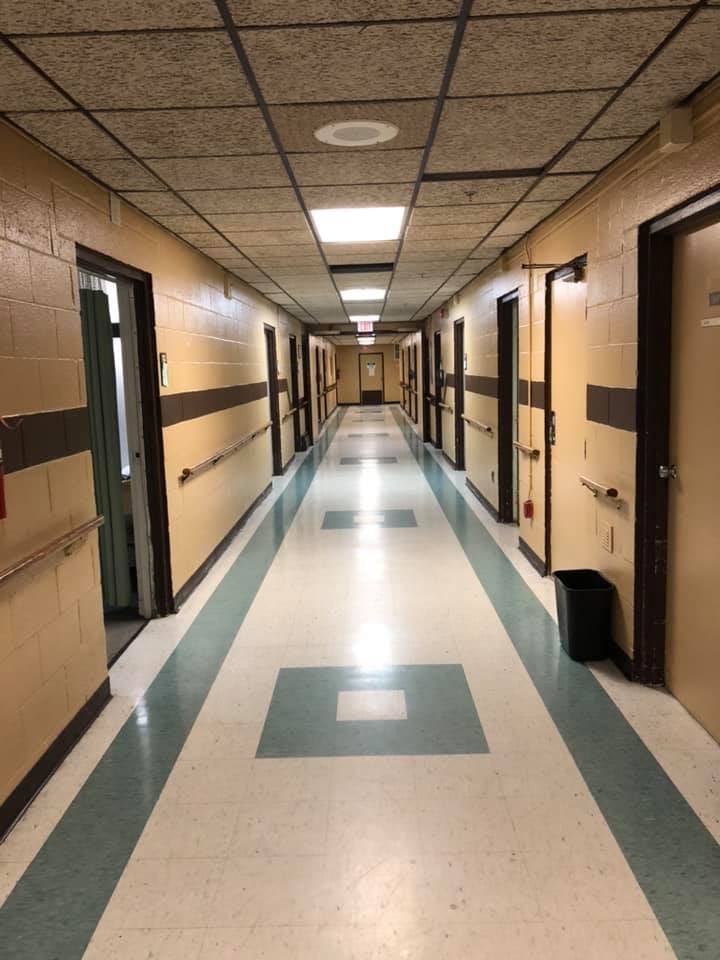 A long, empty hallway with doors along each side and fluorescent lights overhead.