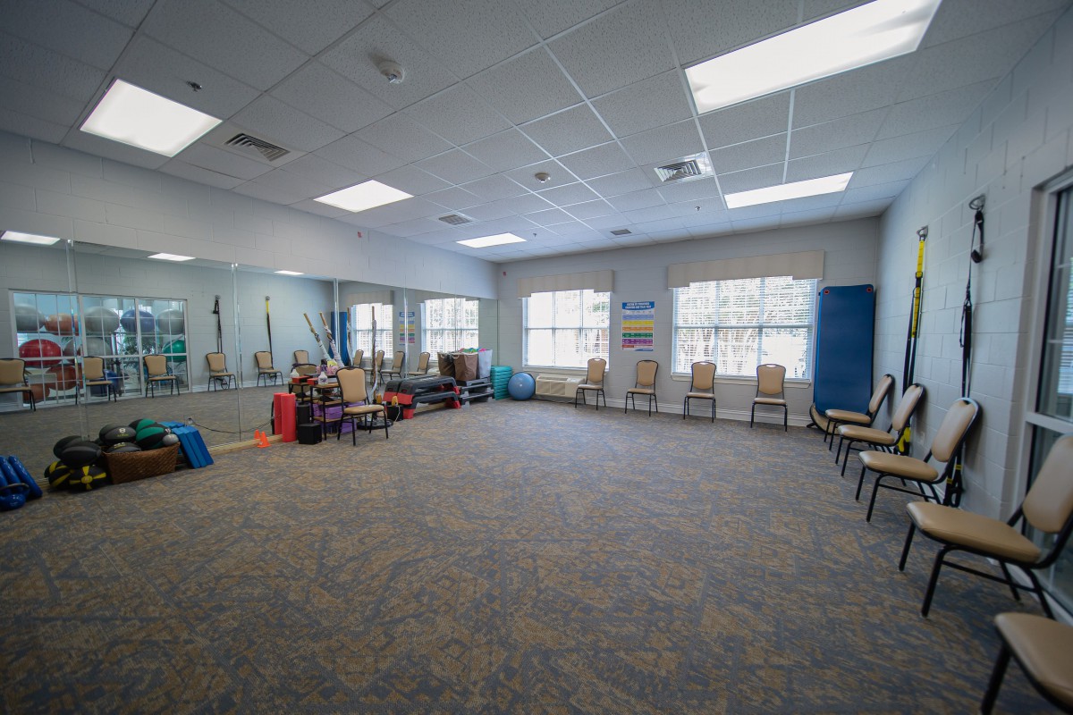 A spacious fitness room with chairs, mirrors, and exercise equipment.
