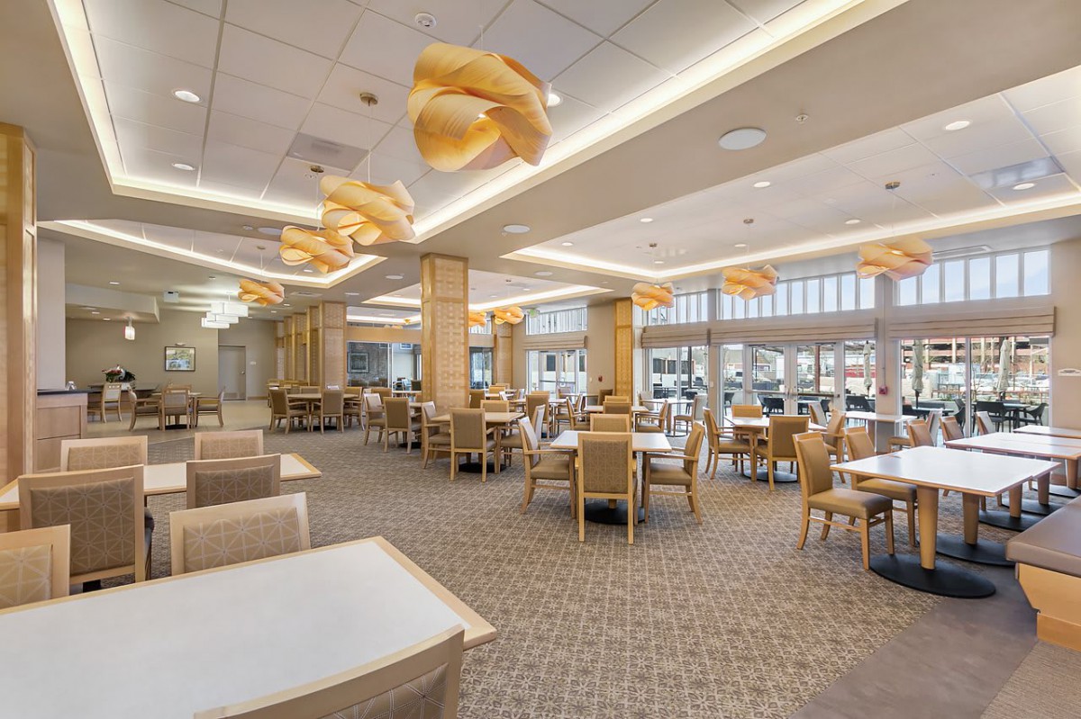 A spacious and modern dining area with stylish overhead lighting and neatly arranged tables and chairs.