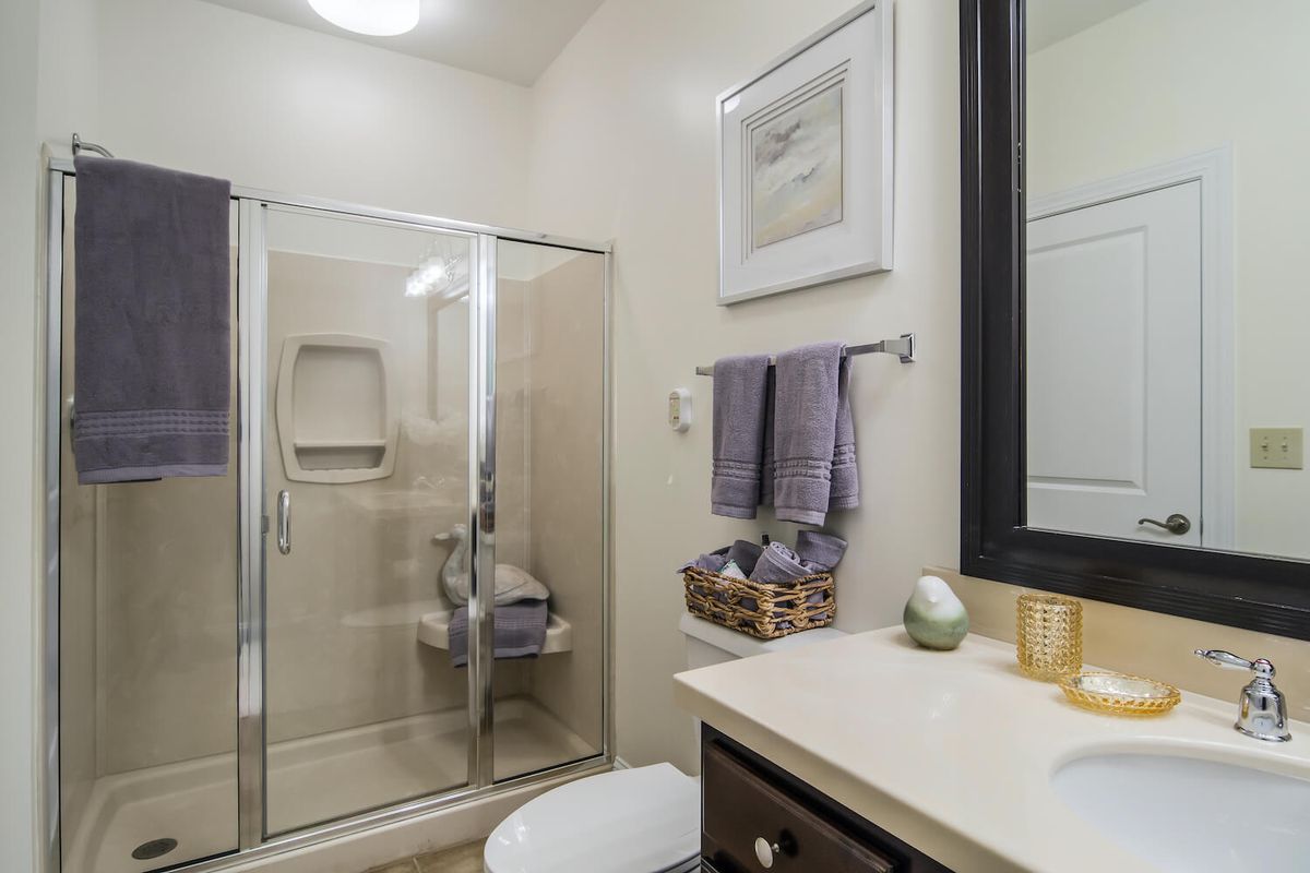 A modern bathroom with a glass shower enclosure, sink, and neatly arranged towels.