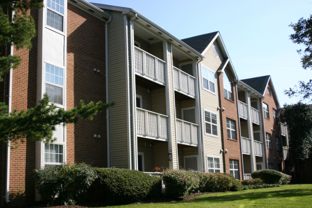 A view of a multi-story apartment building with balconies and well-maintained landscaping.