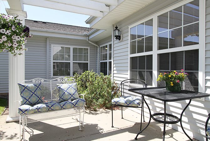 A bright and inviting patio with outdoor seating, plants, and large windows.
