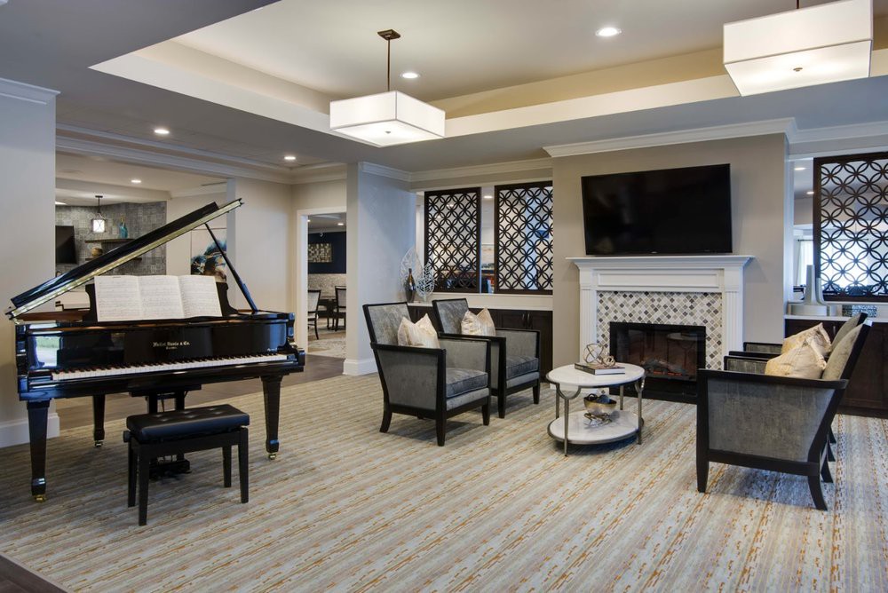 A modern living room with a grand piano, fireplace, and stylish furniture.