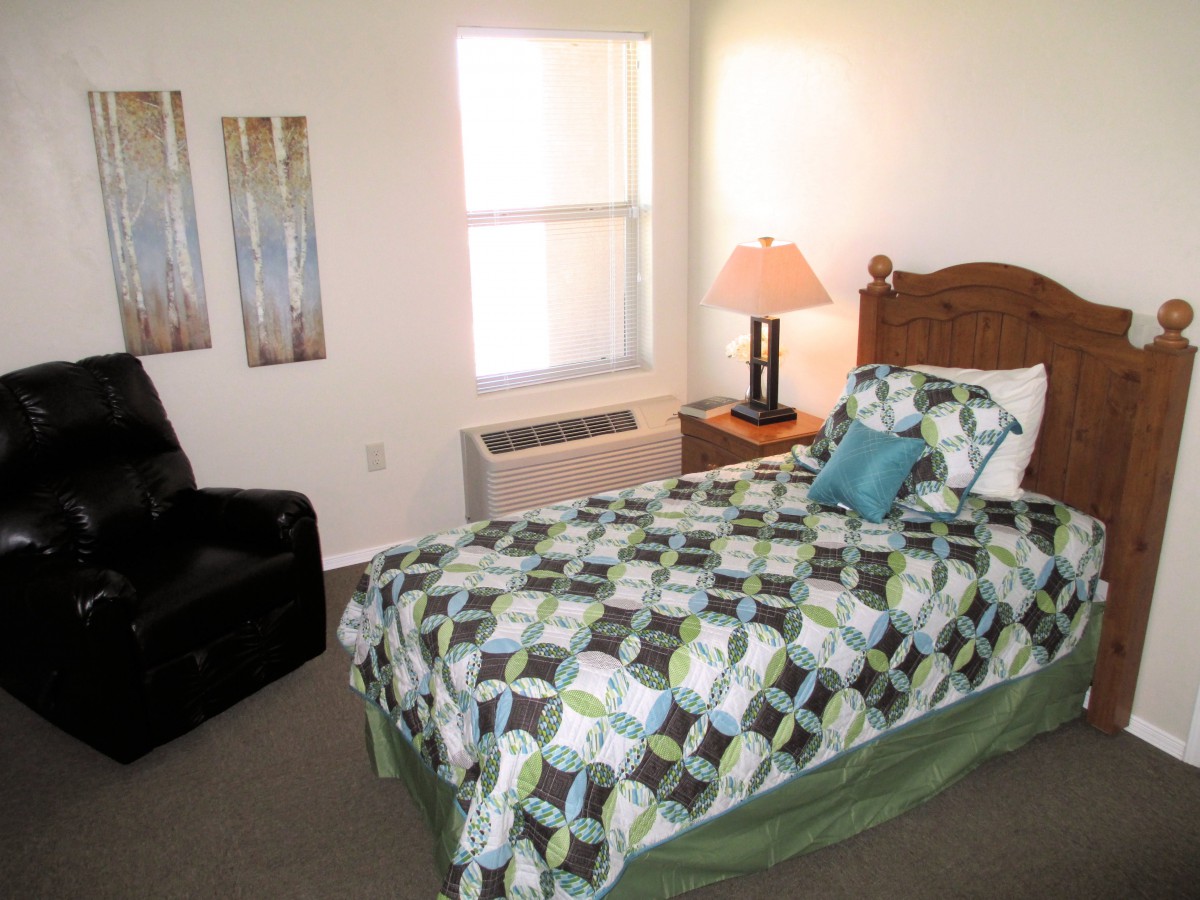 A cozy bedroom with a single bed, decorative bedding, and a bedside lamp.