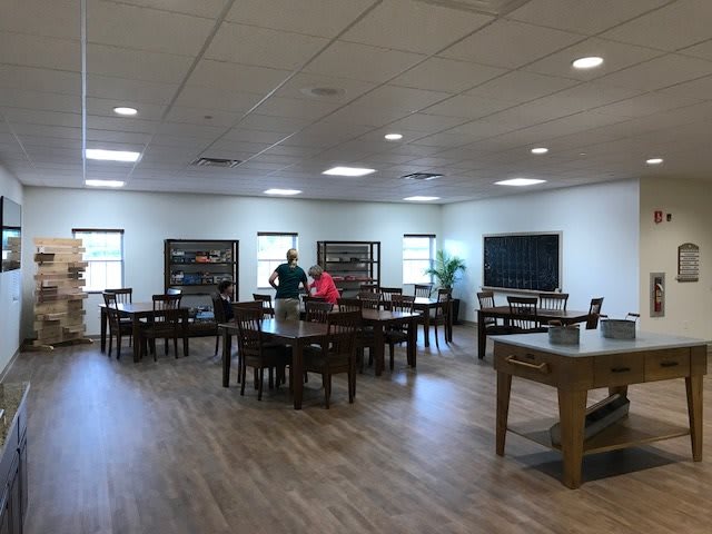 A spacious library interior with tables and bookshelves, where people are engaged in activities.