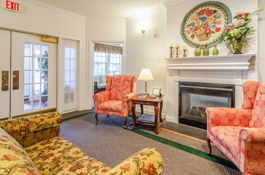 A cozy traditional-style living room with a fireplace, armchairs, and decorative elements.