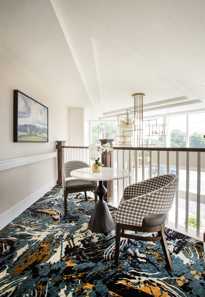 A modern seating area with stylish chairs and a small table, illuminated by natural light through large windows.