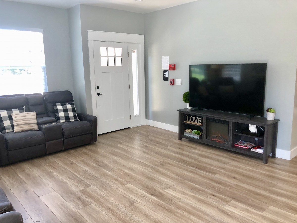 A minimalist living room with modern decor, featuring a sofa, a large television, and hardwood flooring.
