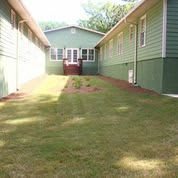 A view of the exterior of a residential building with green siding and a well-maintained lawn.