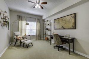 A modern home office with a desk, bookshelf, and large map decor.