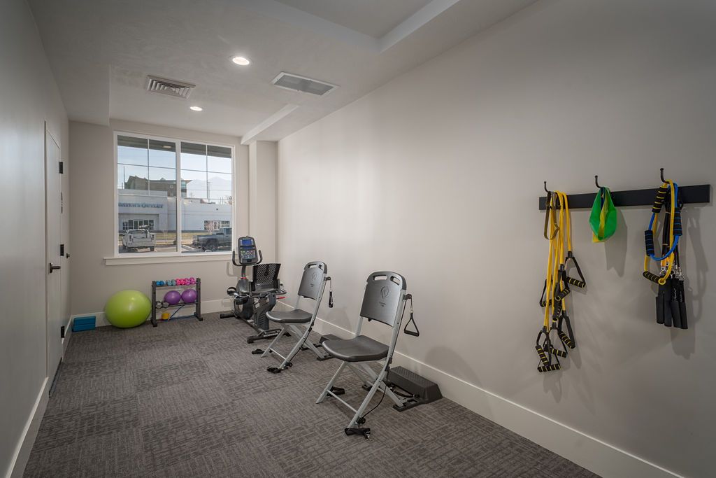 A small home gym with workout equipment, including chairs, resistance bands, and a yoga mat.