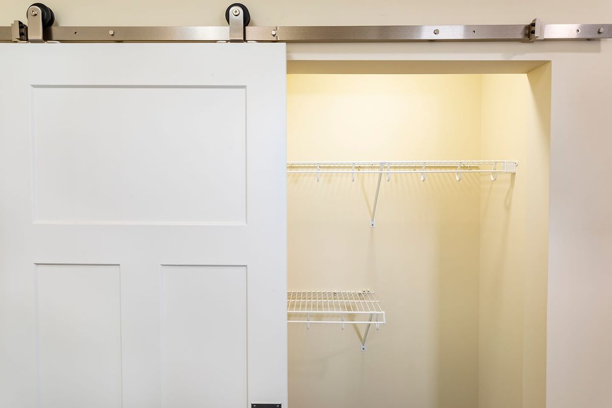A sliding barn door revealing an empty closet with wire shelving.