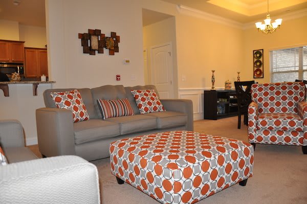A modern living room with a stylish gray sofa and patterned ottoman.