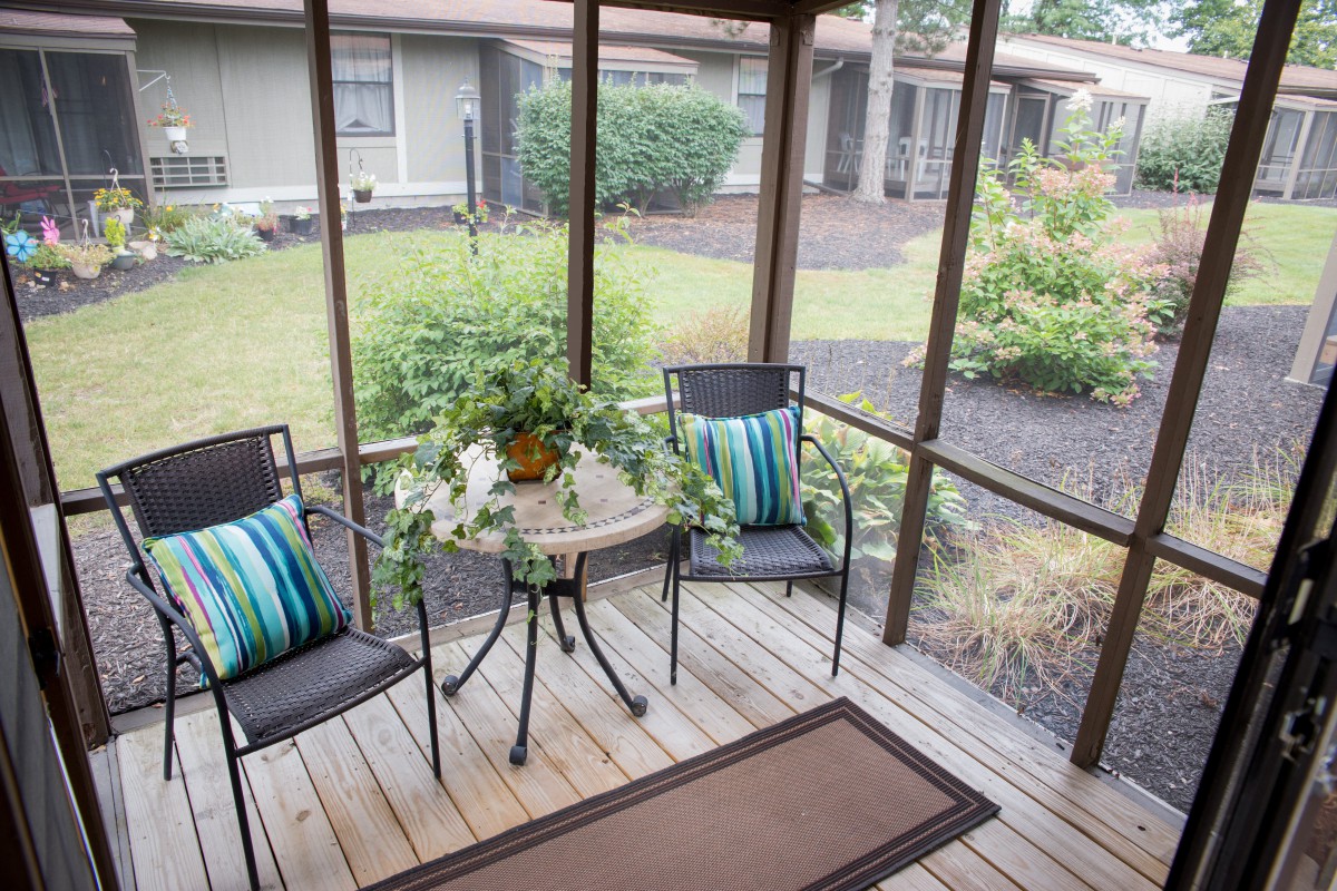 A cozy screened porch with patio furniture and garden view.