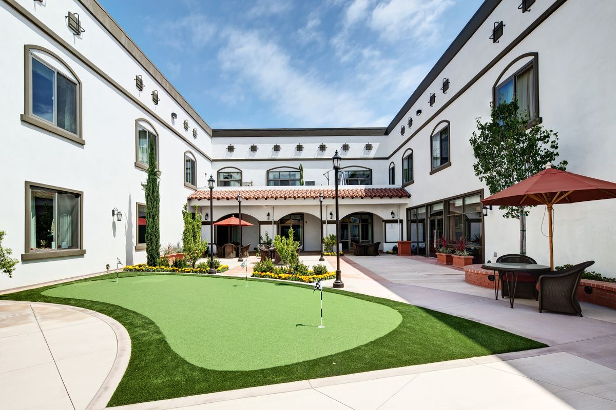 An inviting courtyard with a golf putting green surrounded by a modern building.