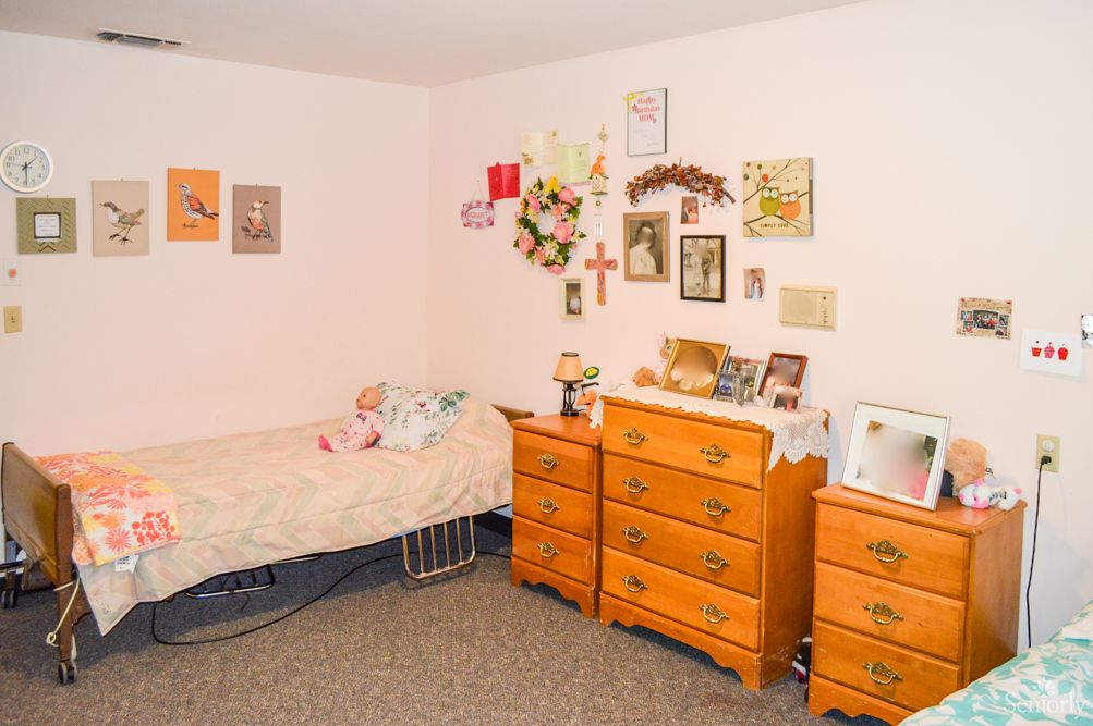 A cozy bedroom with wall decorations and a wooden dresser.