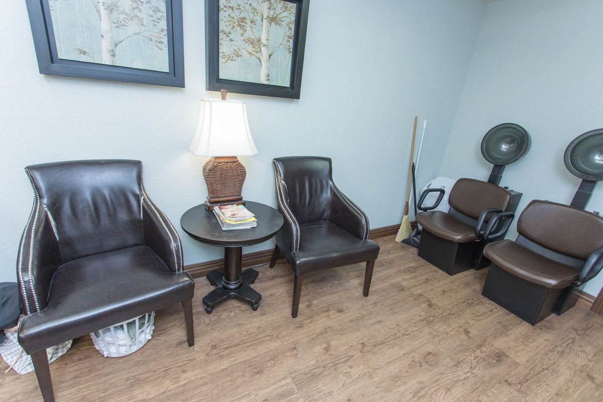 A small waiting room with leather chairs, a central lamp, and decorative artwork on the wall.