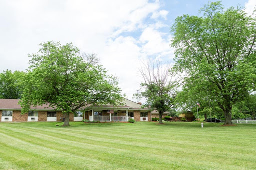 A beautiful house surrounded by a well-maintained lawn and trees under a cloudy sky.
