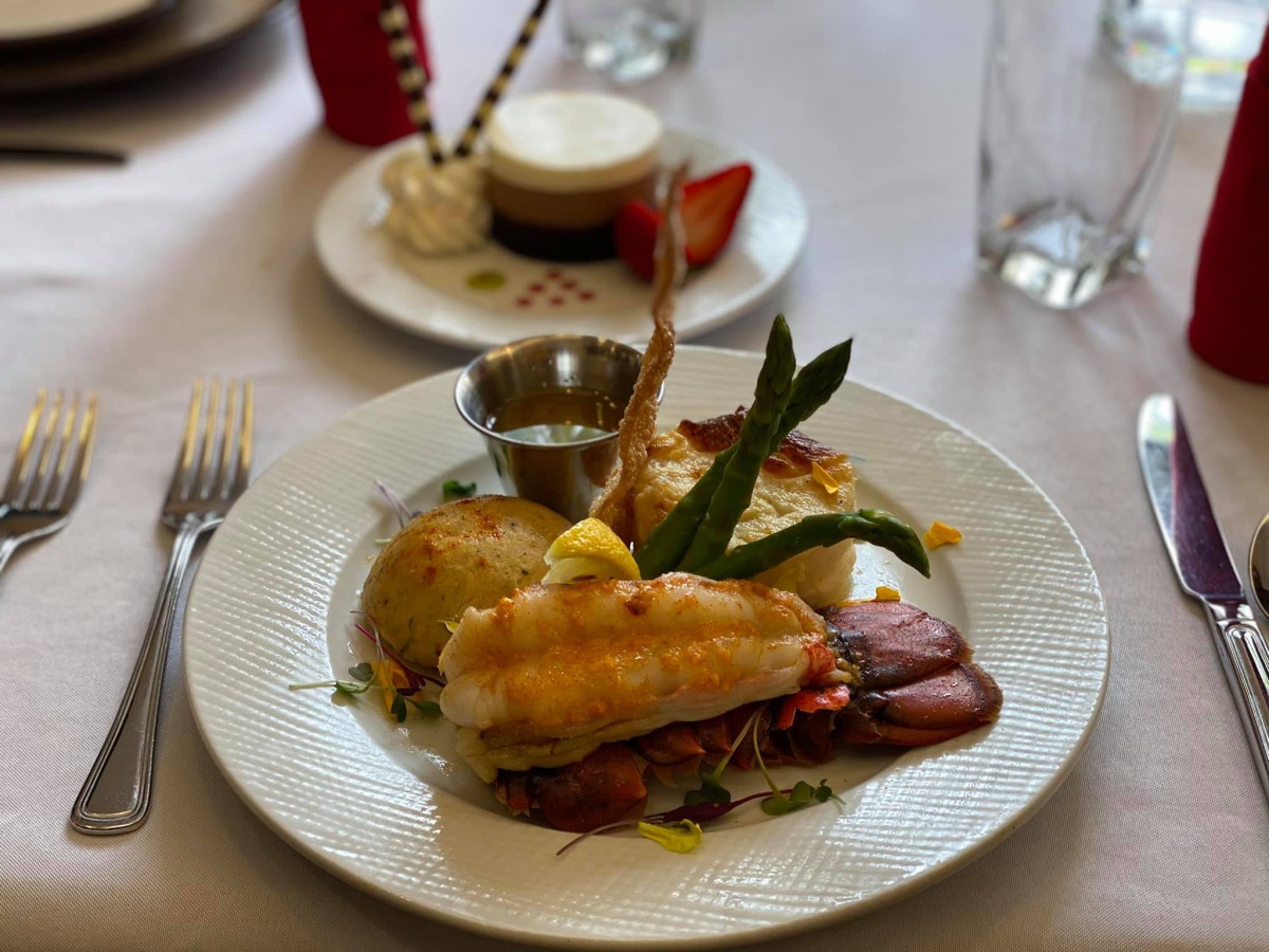 A gourmet meal featuring steak and lobster, elegantly plated with side dishes.