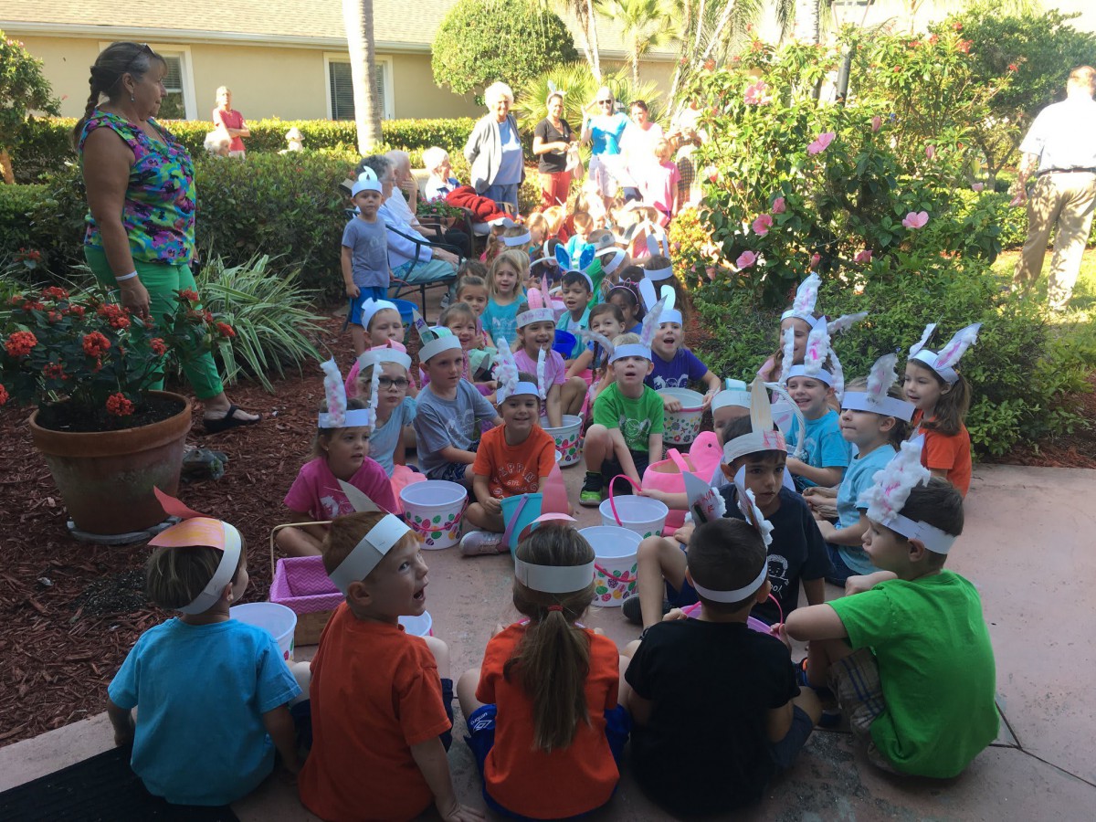 A group of children gathered outdoors, wearing colorful hats in a garden setting.