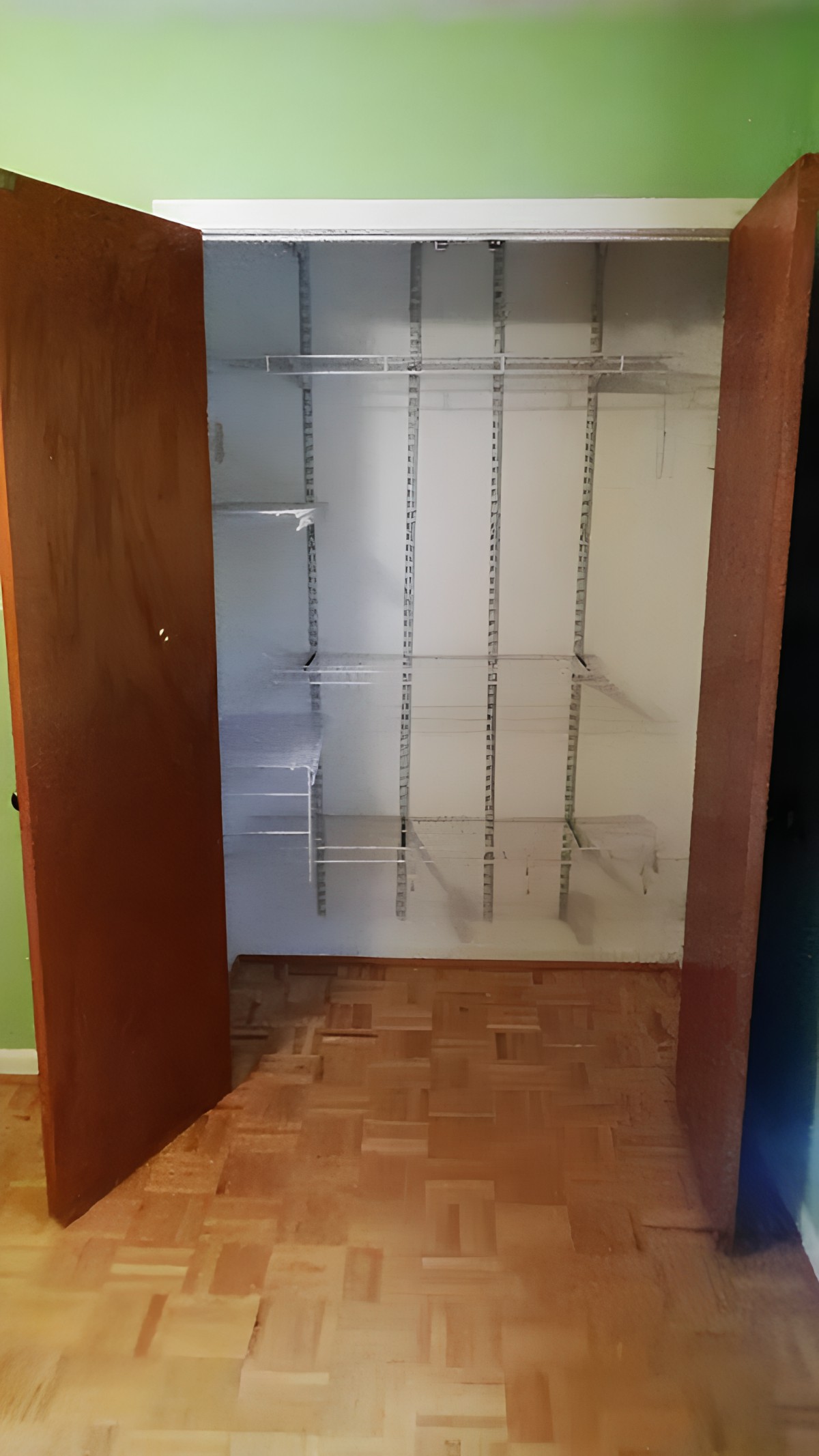 An empty closet with built-in shelves and hanging rods.