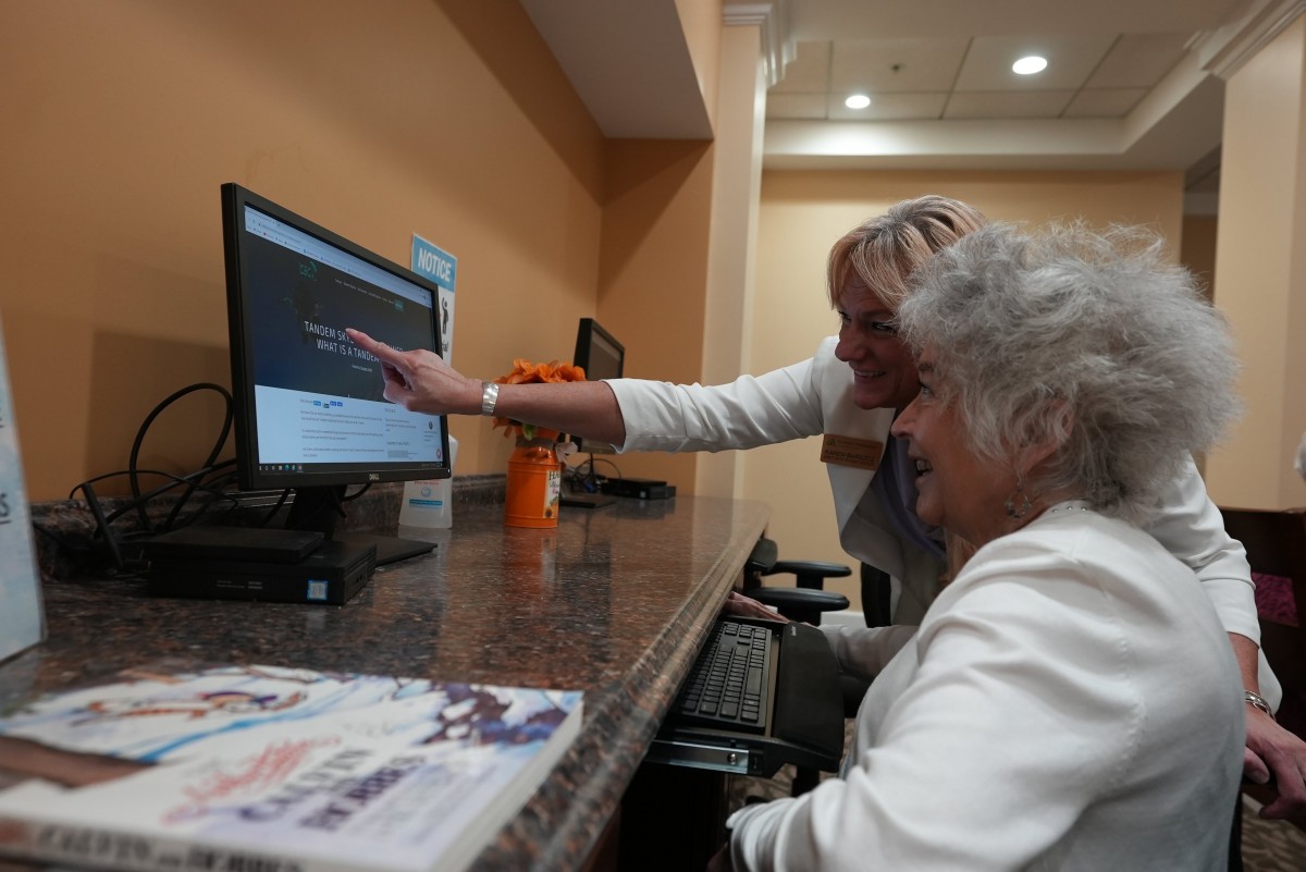 An elderly person receives guidance on using a computer.