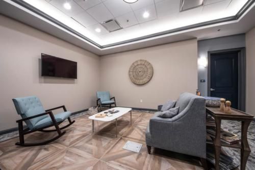 A modern waiting room featuring comfortable seating and a wall-mounted TV.