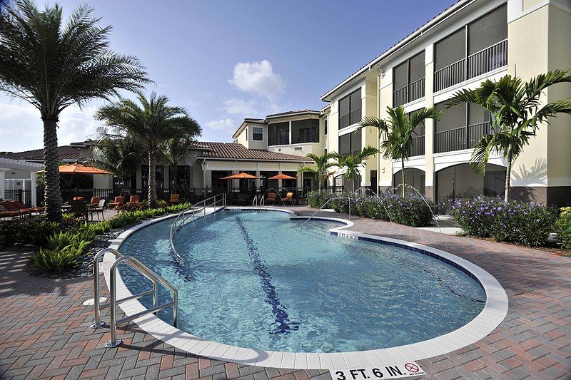 A luxurious resort with a sparkling outdoor swimming pool surrounded by palm trees.
