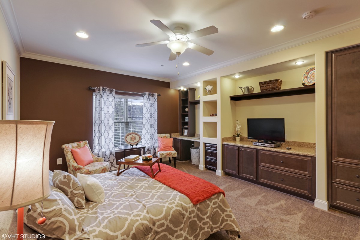 A cozy bedroom with a bed, TV, and seating area.