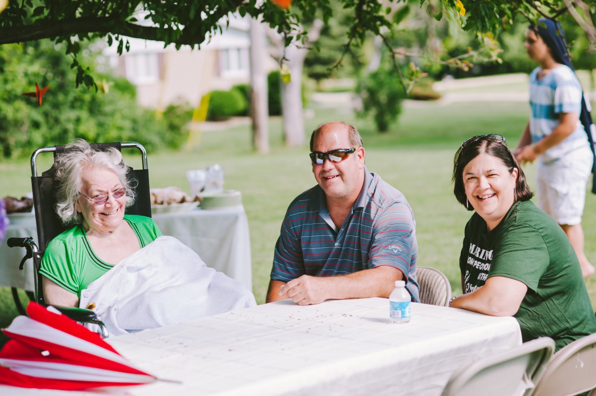 A group of people enjoying a picnic outdoors under the shade of trees.