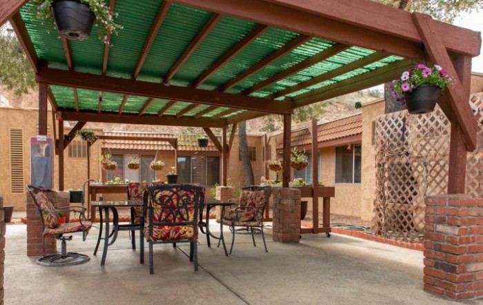 A cozy patio area featuring a pergola, outdoor furniture, and brick accents.