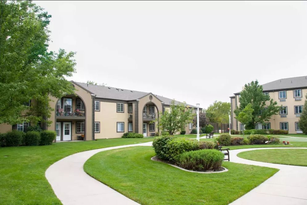 A well-maintained apartment complex featuring lush greenery and paved walkways.