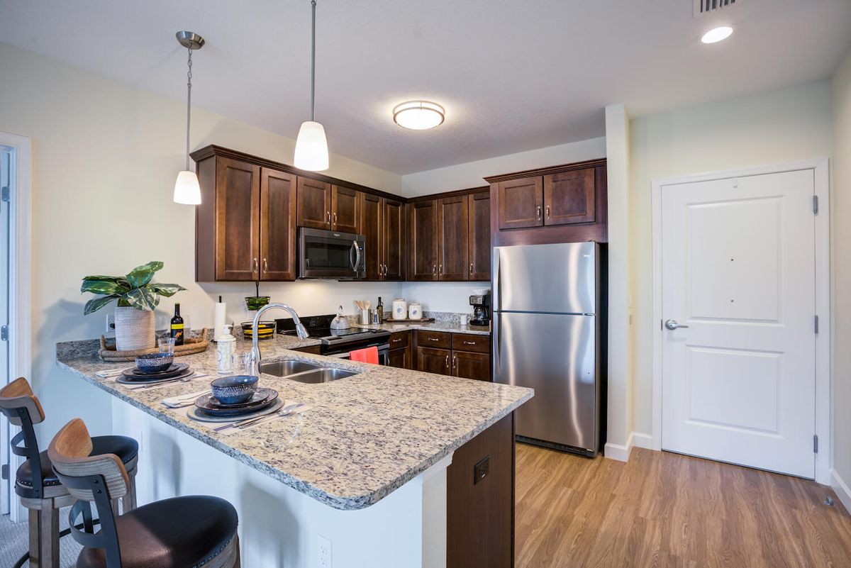 A modern kitchen with wooden cabinets, granite countertops, and stainless steel appliances.