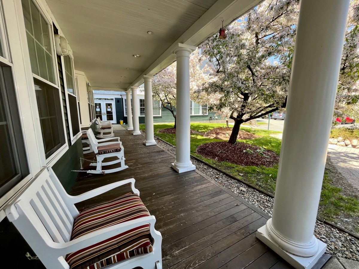 A charming porch with rocking chairs, surrounded by columns and a lush garden.