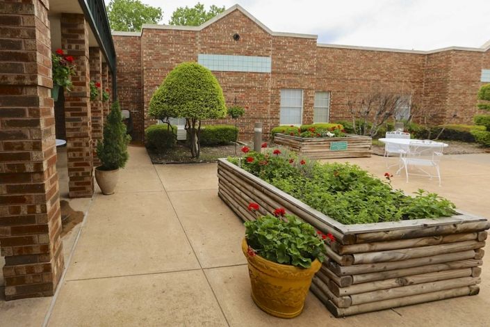 Outdoor garden area with planter boxes and a brick building in the background.