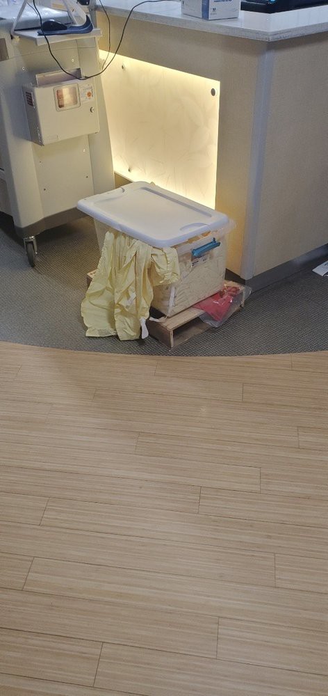 A hospital cleaning cart with a yellow gown draped over it.
