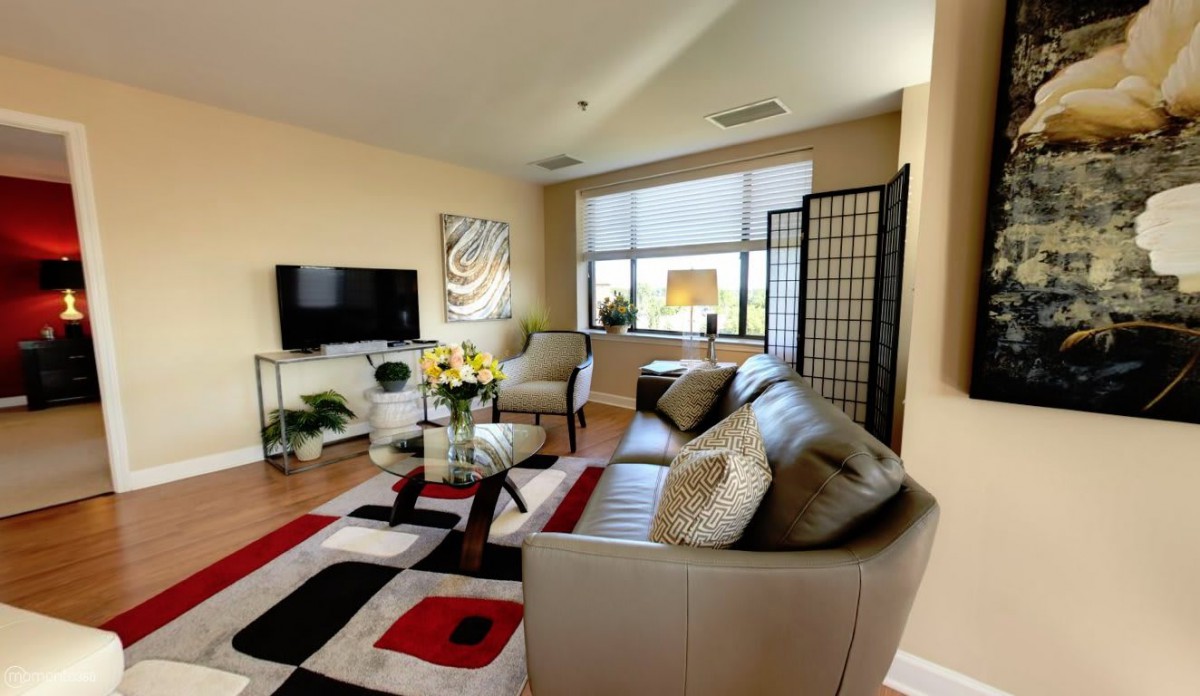 A modern living room with a stylish leather sofa, decorative rug, and mounted television.