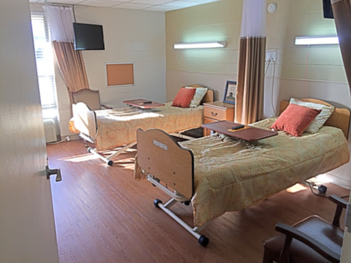 A shared patient room in a healthcare facility, featuring two beds with comfortable bedding and a warm ambiance.